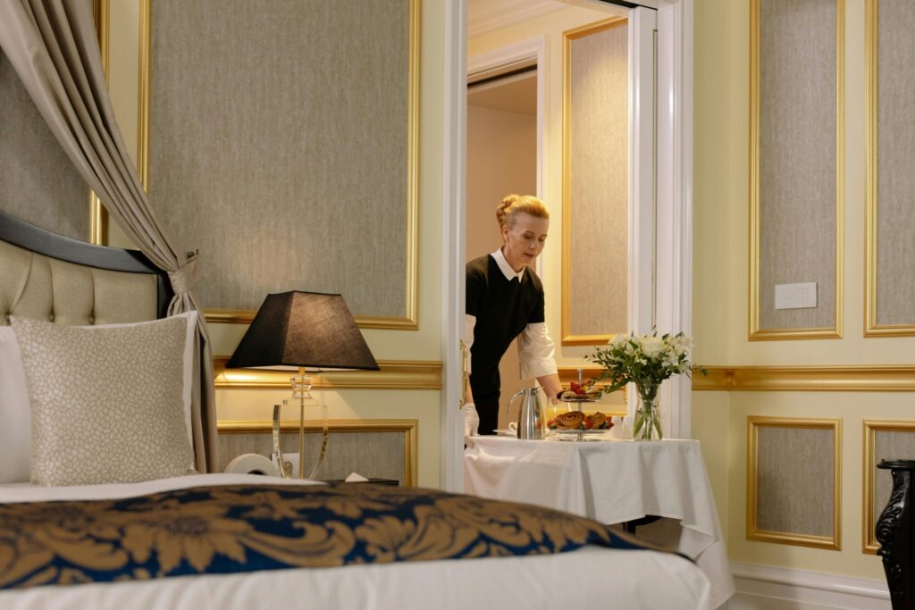 A room service attendant in view about to roll in a trolley of food into a hotel room